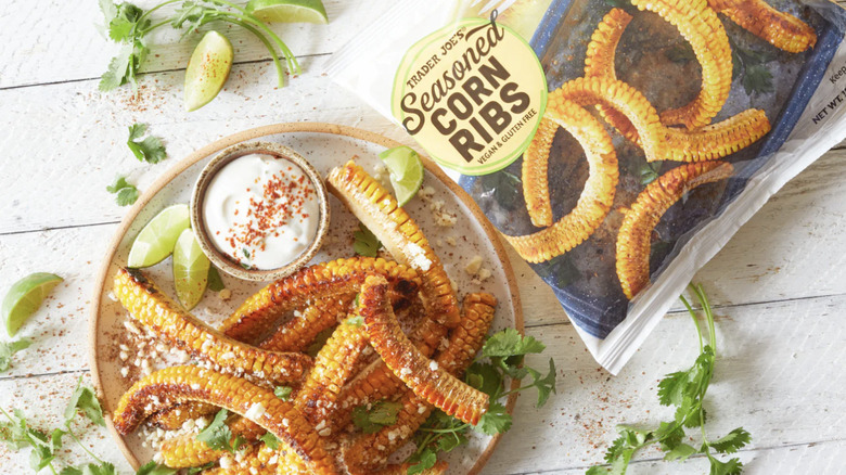 Trader Joe's Seasoned Corn Ribs bad next to a plate of Seasoned Corn Ribs with lime and dip