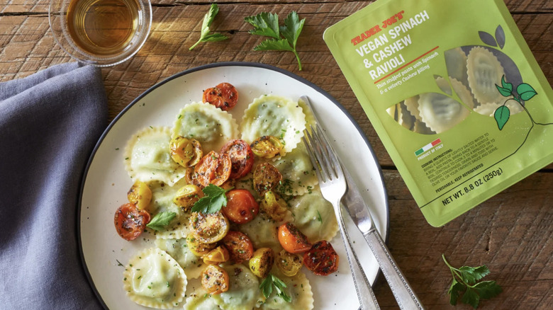 Ravioli on a plate with tomatoes, next to a package of Vegan Spinach & Cashew Ravioli