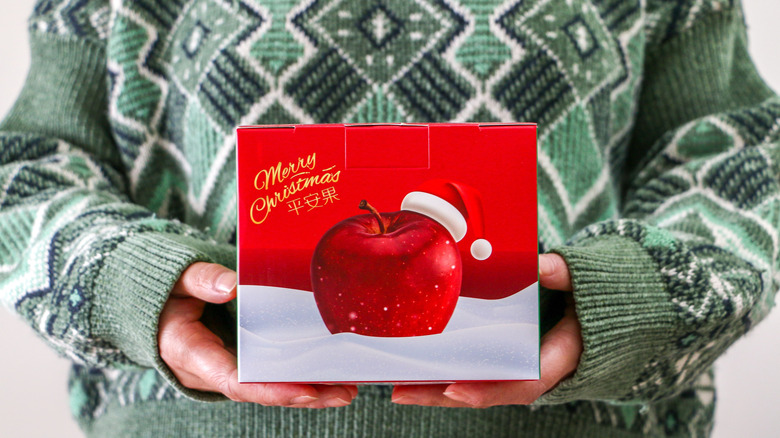 A person holds a Christmas apple box