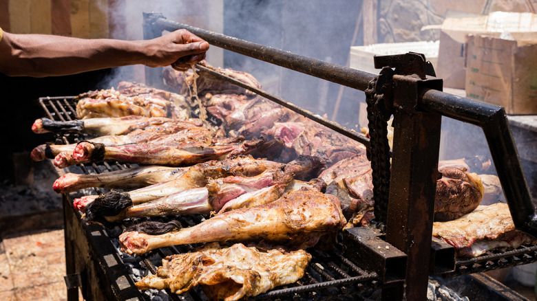 A person roasts a goat on a grill.