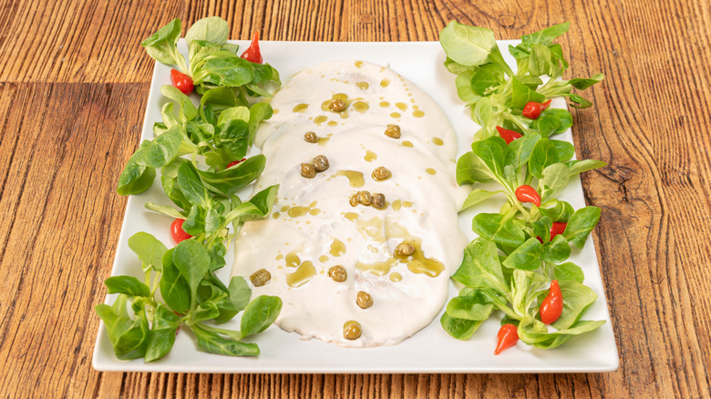 A plate of vitel toné is lined on either side with salad.