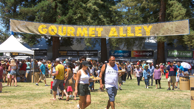 A man and woman walk through Gourmet Alley at the Gilroy Garlic Festival