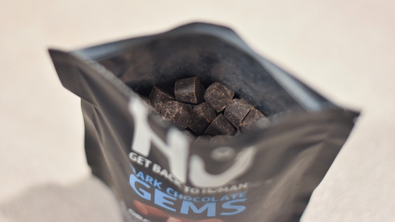 An opened bag of Hu dark chocolate gems form above, showing small chocolates inside