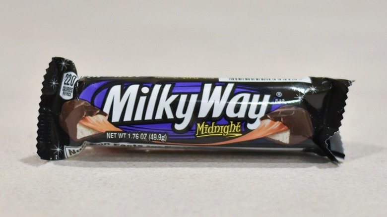 A Milky Way midnight candy bar on a white counter