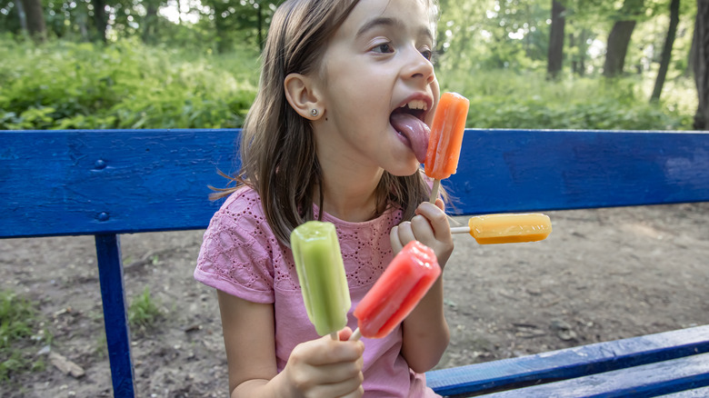 Child holding four popsicles 