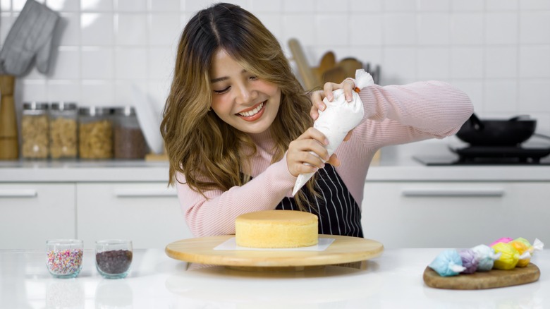 Woman piping frosting on a cake