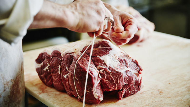 Butcher tying cut of beef