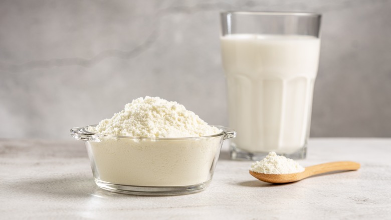 Bowl of milk powder beside glass of milk