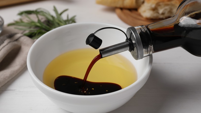 Pouring balsamic vinegar into a bowl of olive oil