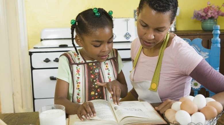Woman and girl reading cookbook