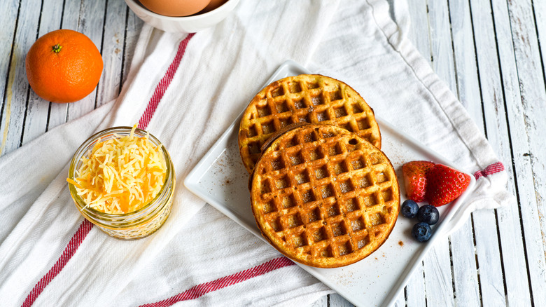 waffles sit against white background beside jar of shredded cheese