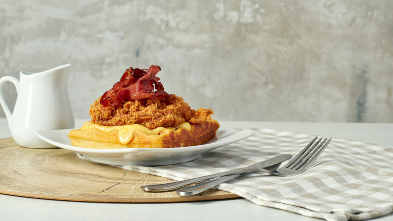 a plate of fried chicken and waffles is topped with crispy bacon