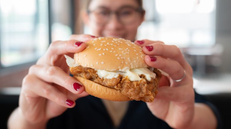 woman holding a fast food chicken sandwich