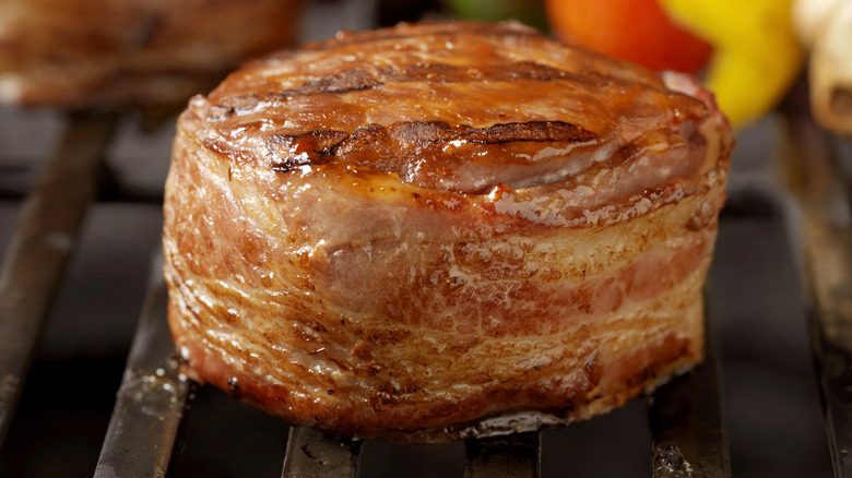 A steak wrapped in bacon on the grill