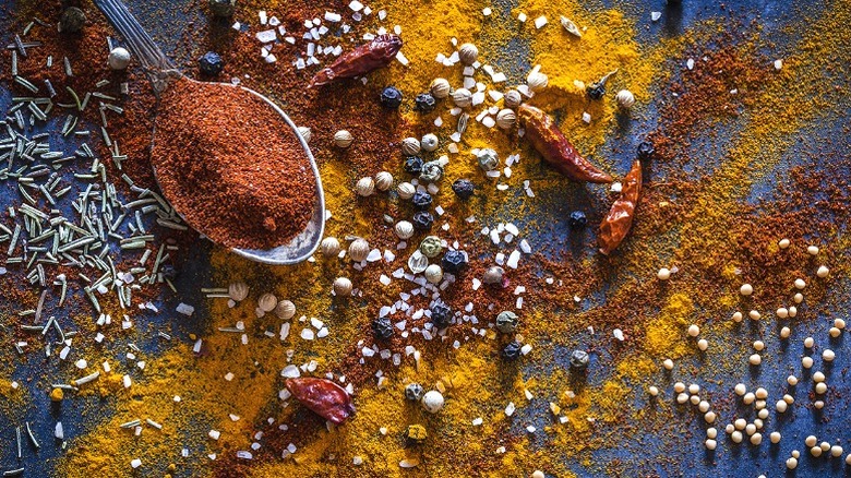 Lots of whole spices poured out over a blue surface