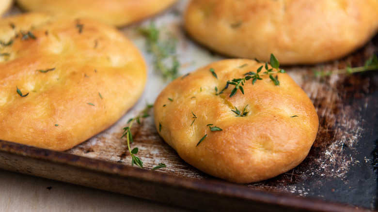 Focaccia topped with thyme on a baking sheet