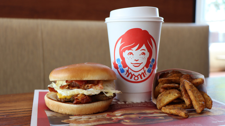 Wendy's Breakfast Baconator is pictured with potatoes and a coffee cup all on a tray.