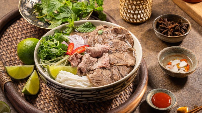 Bowl of beef pho with star anise, lime, and other toppings