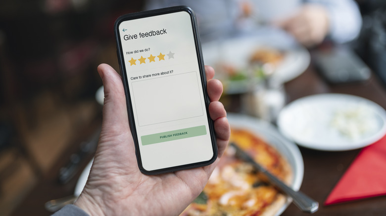 A person holding a phone showing a restaurant review app.