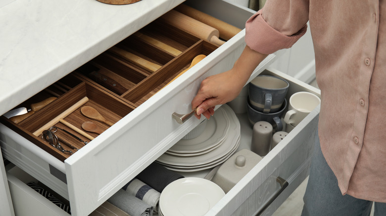 Woman opening deep kitchen drawers.