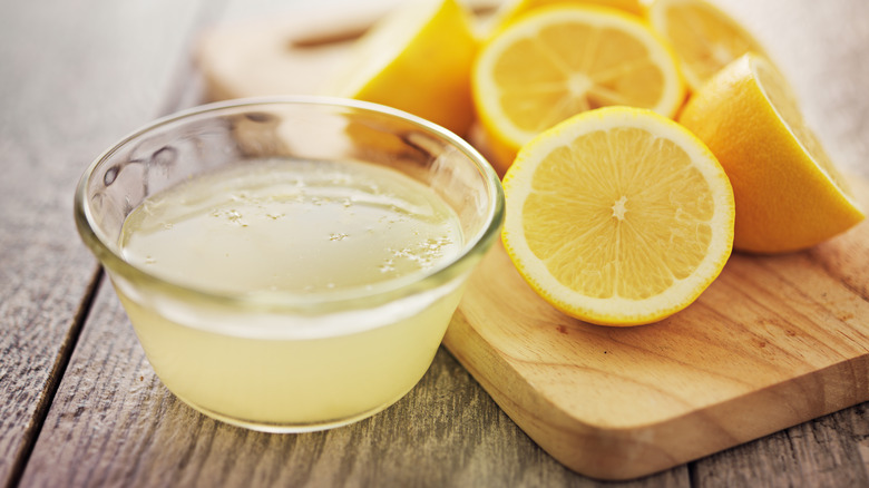 a bowl of lemon juice with lemon halves on the side