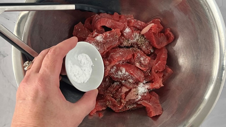 baking soda going into bowl with beef