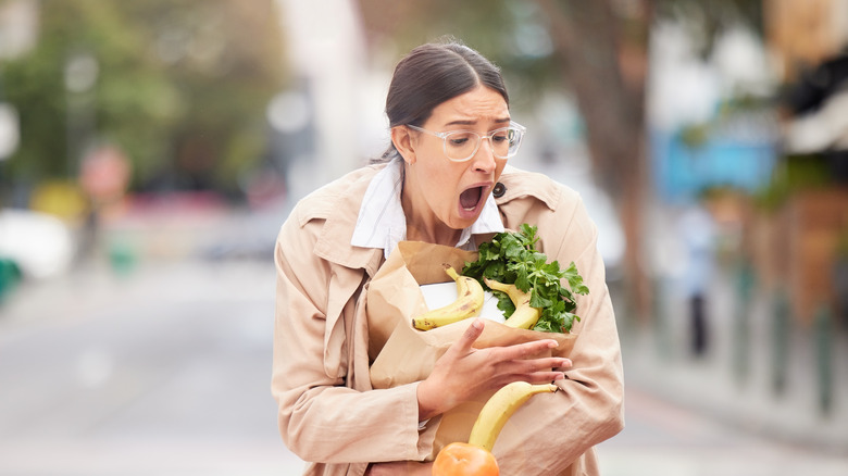 woman is alarmed as her grocery bag breaks