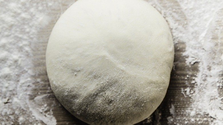 Pizza dough ball on a floured surface