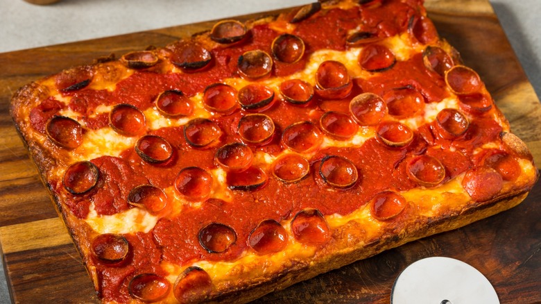 A rectangular Detroit-style pizza on a wooden board