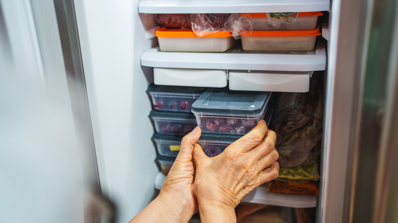 Person putting storage containers in freezer