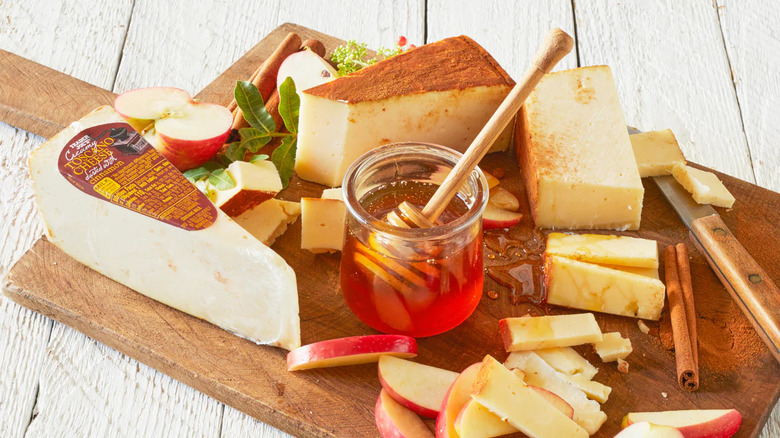 charcuterie board with cheese, apples, and honey