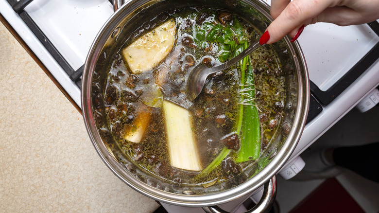 Person stirring vegetables in stockpot