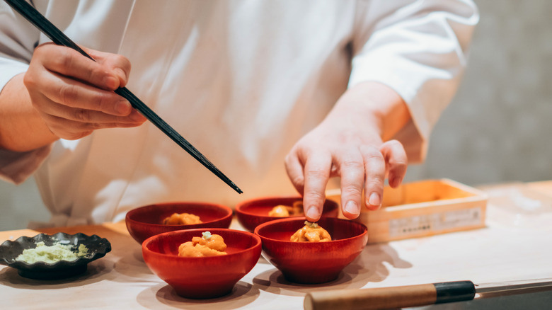 A chef using chopsticks to prepare bowls