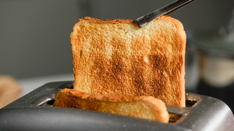 Chopsticks pulling bread from a toaster