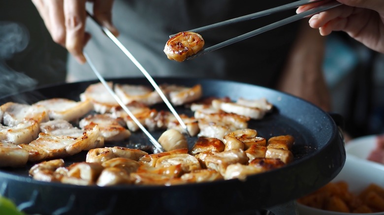 flipping food with chopsticks on a table grill