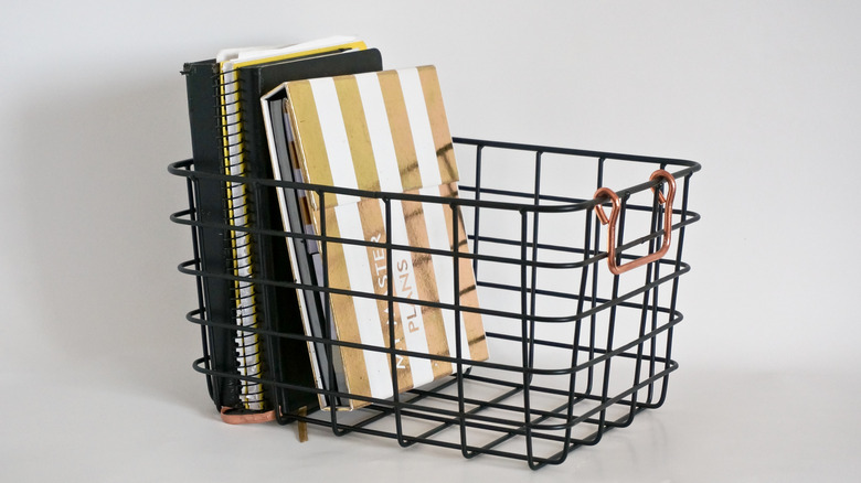 A wire basket with notebooks inside
