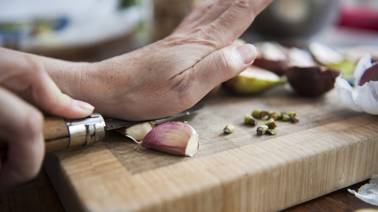 hand smashing cloves of garlic with knife