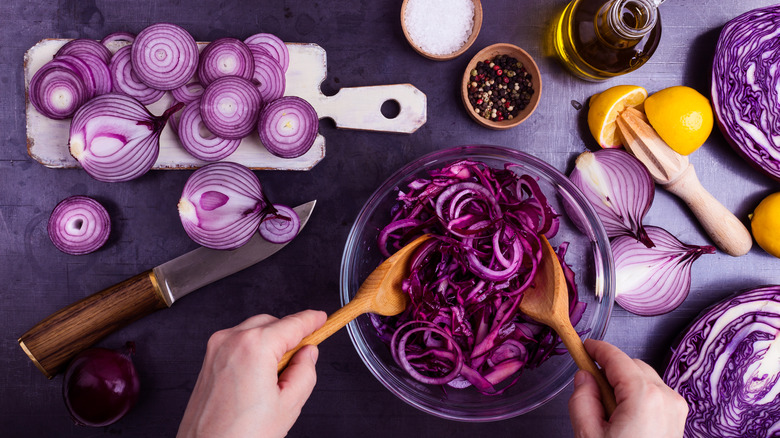 hands tossing purple onions in bowl