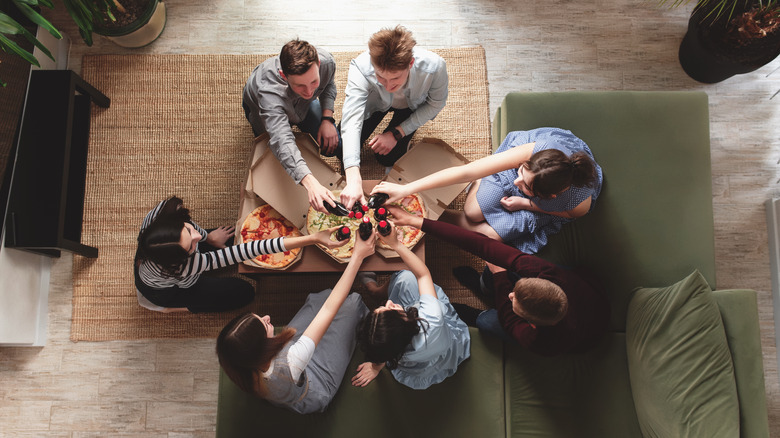 Overhead view of friends sitting in circle and clinking bottles