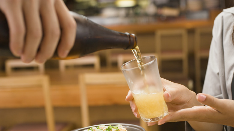 Person pouring drink into another person's glass