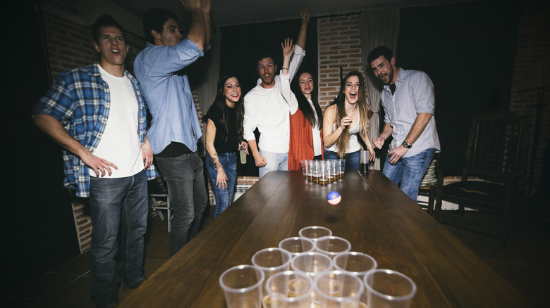 Group of men and women cheering while playing beer pong