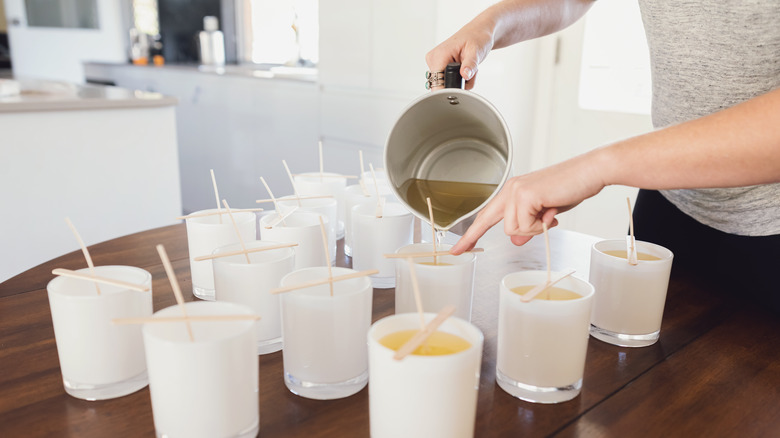 Cups and wicks on table with wax being poured into them