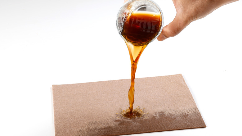 Hand pouring coffee onto a sheet of fabric