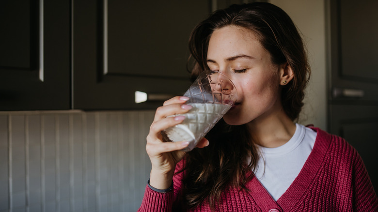 A woman drinking a glass of oat milk