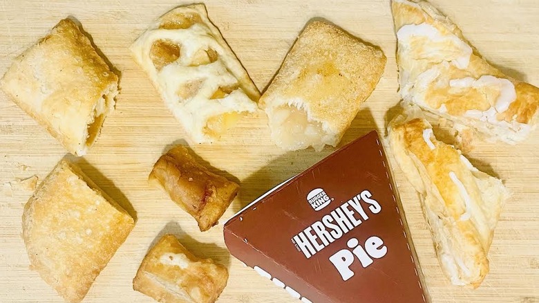 Assorted half eaten fast food pies on wooden cutting board