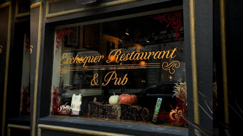 The exterior of the Exchequer Restaurant & Pub with pumpkins viewed through the large window