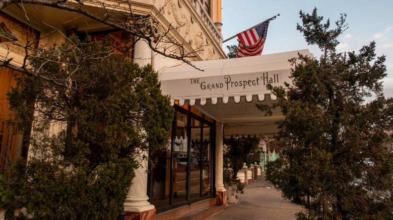 The exterior of The Grand Prospect Hall with a white awning and green trees