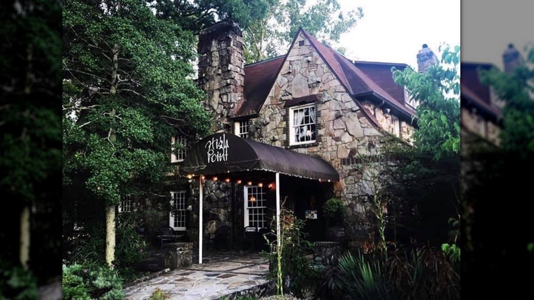 The outside front of High Point Restaurant with stone walls and green trees