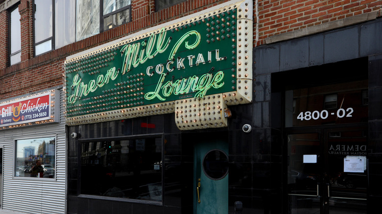 The exterior of The Green Mill cocktail lounge with a lit sign and green front door