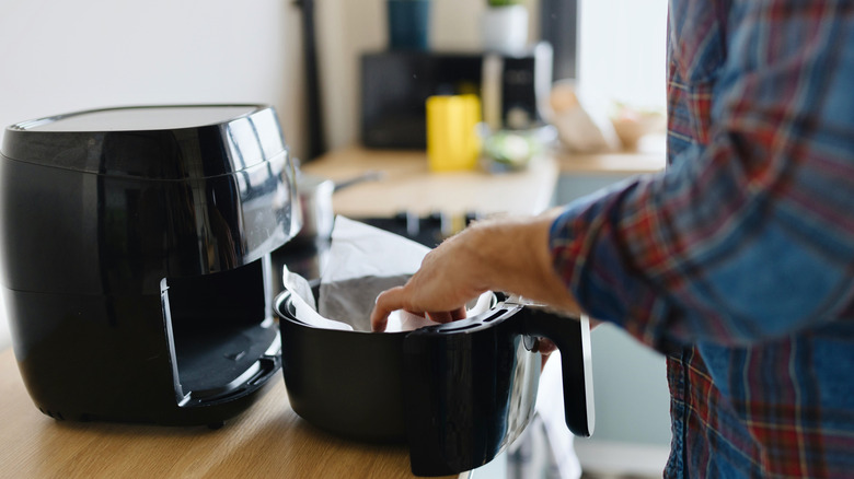 Person putting parchment paper in air fryer to keep it clean